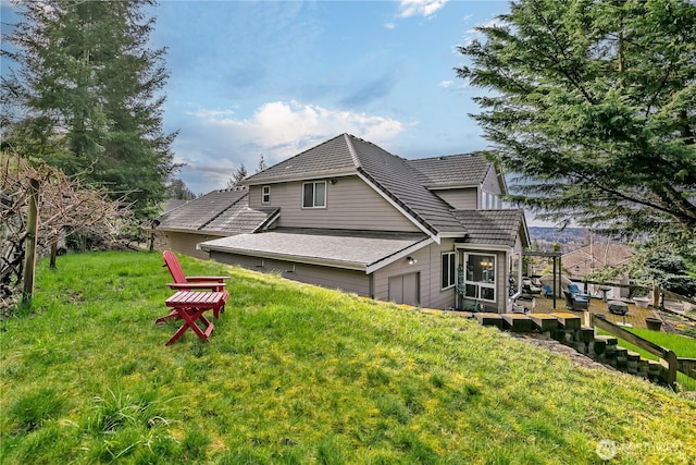 back of house featuring a garage, a tiled roof, and a yard