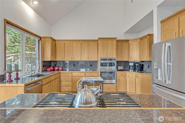 kitchen featuring decorative backsplash, light brown cabinets, appliances with stainless steel finishes, and a sink