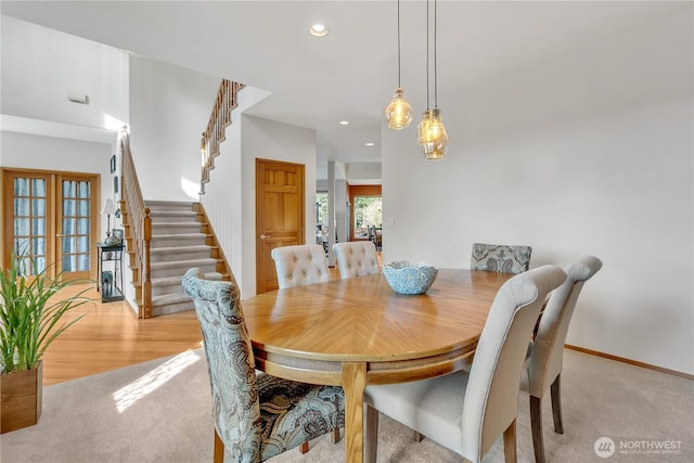 dining room with recessed lighting, baseboards, light carpet, and stairs