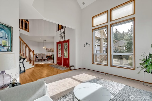 entryway with stairway, baseboards, visible vents, and high vaulted ceiling