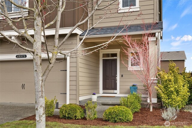 view of exterior entry with a shingled roof