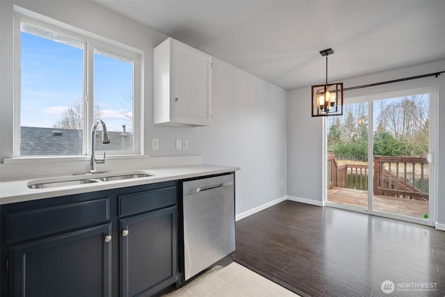 kitchen featuring baseboards, decorative light fixtures, dishwasher, light countertops, and a sink