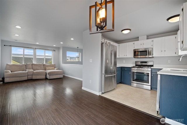 kitchen featuring a sink, light countertops, appliances with stainless steel finishes, blue cabinets, and open floor plan