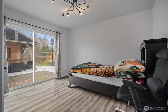 bedroom featuring a notable chandelier, wood finished floors, and access to outside