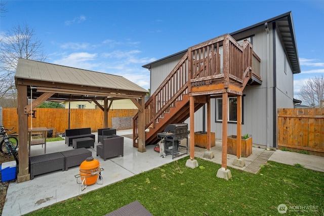 rear view of property with stairs, outdoor lounge area, a fenced backyard, a yard, and a patio