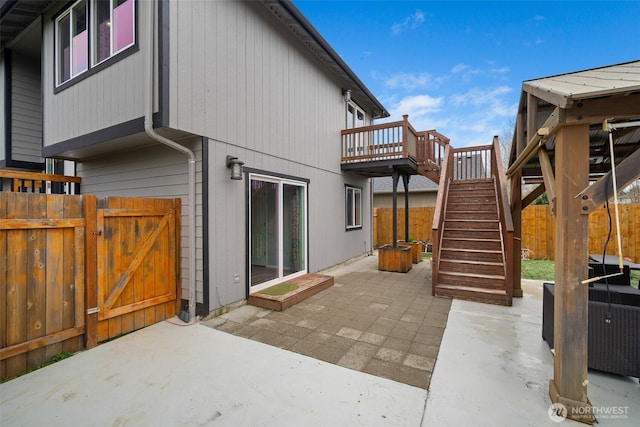 rear view of house featuring fence, stairs, a deck, a patio, and a gate