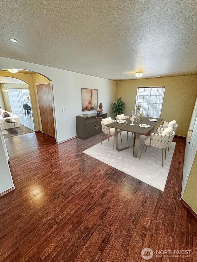 living area featuring wood finished floors, arched walkways, and a textured ceiling