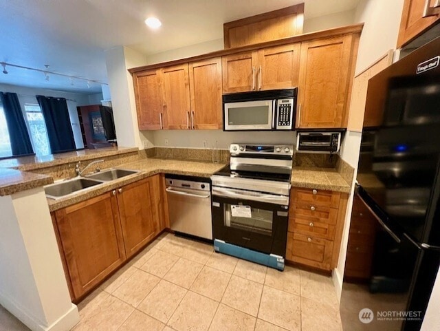 123 Queen Anne Ave N Unit 307, Seattle, WA 98109 - kitchen featuring light tile patterned floors, brown cabinetry, recessed lighting, a sink, and appliances with stainless steel finishes
