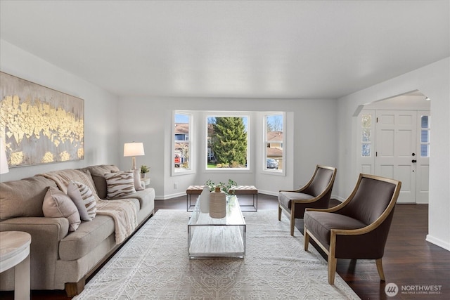 living area with baseboards, arched walkways, and wood finished floors