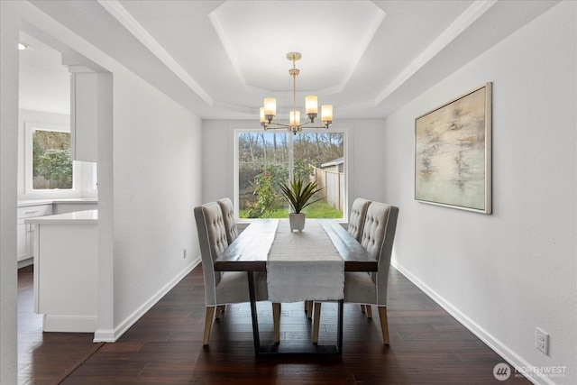 dining space featuring a tray ceiling, baseboards, a notable chandelier, and dark wood-type flooring