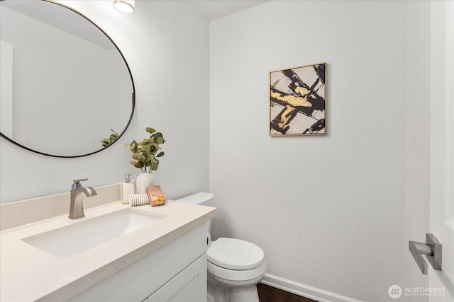 half bathroom featuring baseboards, wood finished floors, toilet, and vanity