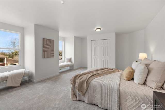 bedroom with a closet, light carpet, baseboards, and multiple windows