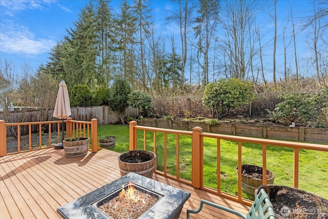 deck featuring a fenced backyard, a fire pit, and a yard