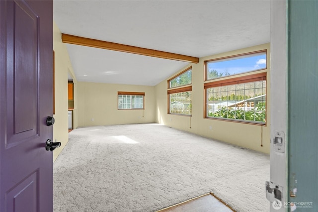empty room featuring lofted ceiling with beams and carpet