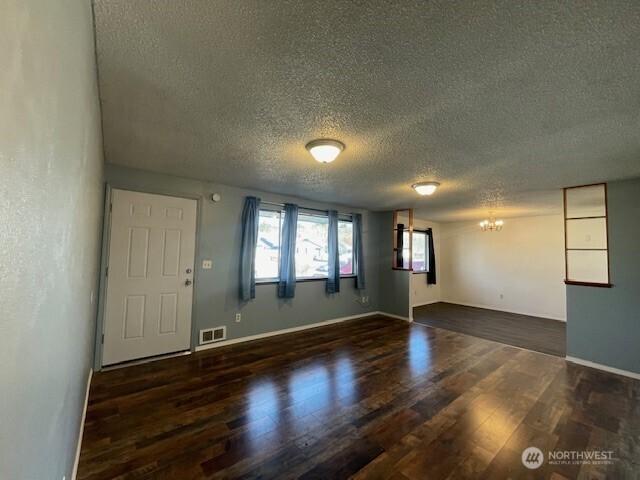 interior space with baseboards, visible vents, an inviting chandelier, and wood finished floors