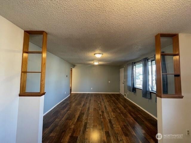 spare room featuring a textured ceiling, baseboards, and wood finished floors