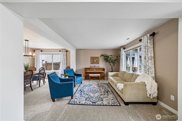 carpeted living room with plenty of natural light, baseboards, visible vents, and a chandelier