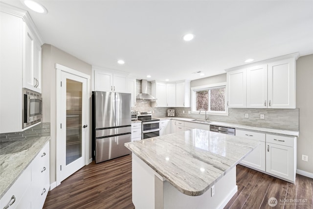 kitchen featuring dark wood-type flooring, a sink, appliances with stainless steel finishes, white cabinets, and wall chimney range hood