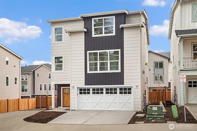 view of front of home featuring an attached garage, concrete driveway, board and batten siding, and fence