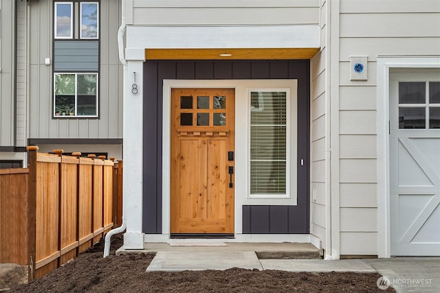 entrance to property featuring board and batten siding and fence