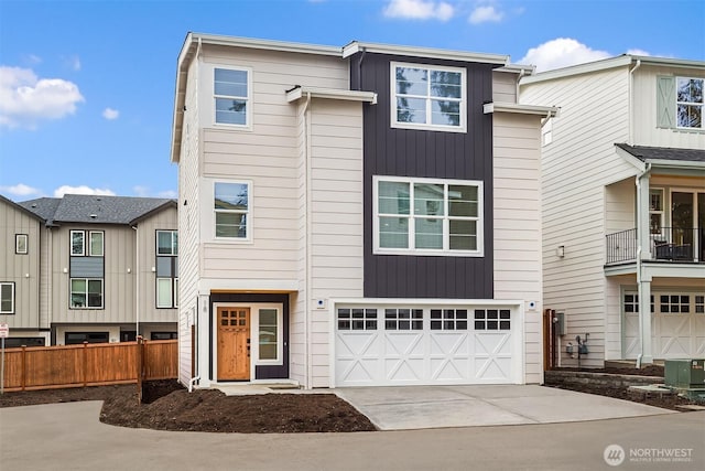 view of property with board and batten siding, fence, a garage, and driveway