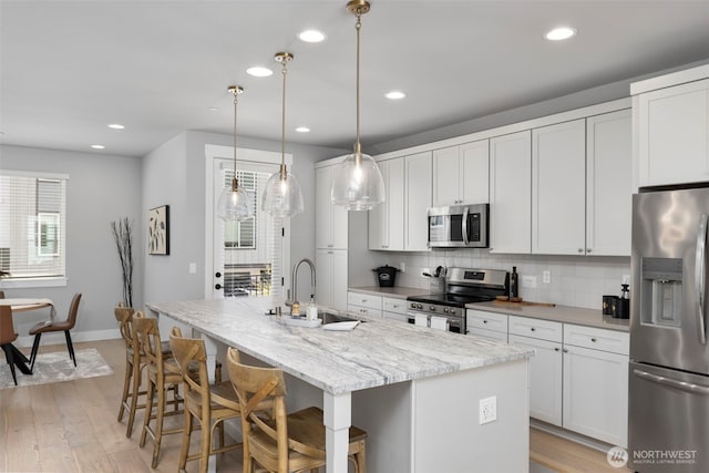 18 160th St SE, Bothell, WA 98012 - kitchen with stainless steel appliances, tasteful backsplash, an island with sink, light wood-style flooring, and white cabinetry