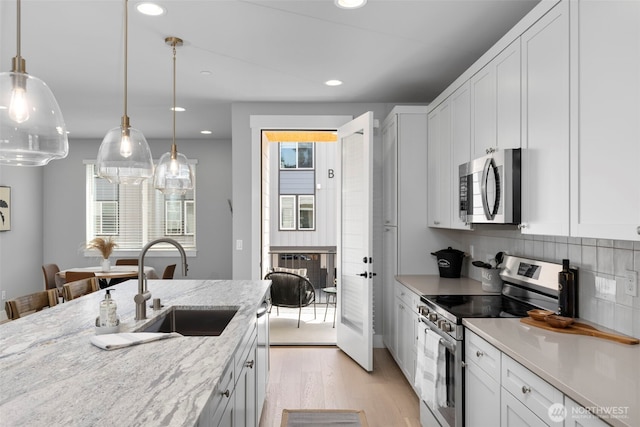 18 160th St SE, Bothell, WA 98012 - kitchen featuring stainless steel appliances, light wood finished floors, white cabinetry, decorative backsplash, and hanging light fixtures