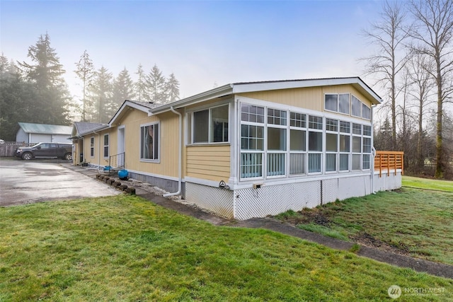 view of home's exterior with a lawn and a sunroom