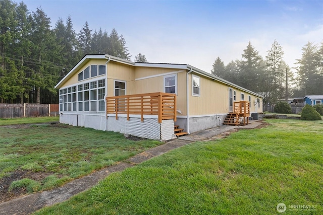 view of side of property featuring a lawn, a wooden deck, and fence
