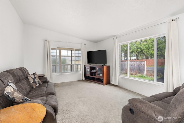 living room featuring vaulted ceiling, carpet, and a healthy amount of sunlight