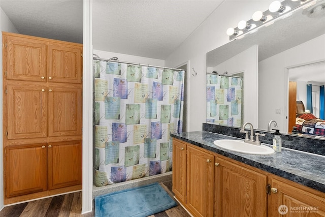 bathroom featuring a shower with shower curtain, a textured ceiling, wood finished floors, and vanity