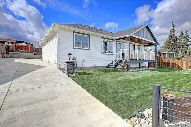 back of house with driveway, a yard, and fence
