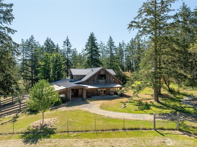 631 Cousins Rd, Lopez Island, WA 98261 - view of front facade with a wooded view, board and batten siding, a front lawn, fence, and metal roof