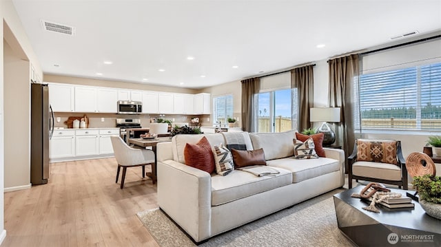 living room featuring recessed lighting, light wood-style floors, and visible vents