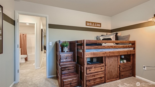 bedroom with ensuite bath, baseboards, and carpet