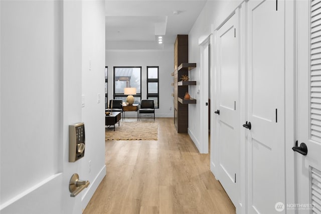 hallway featuring light wood-type flooring and baseboards