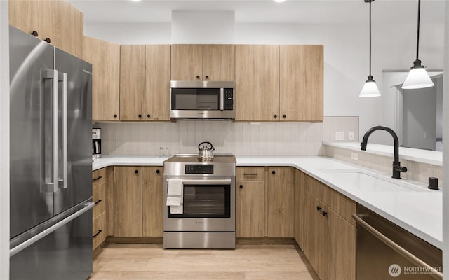 kitchen with decorative backsplash, light wood-type flooring, appliances with stainless steel finishes, and a sink