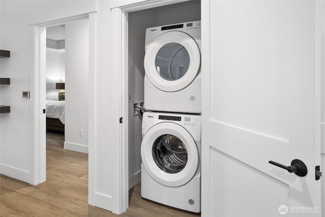 washroom with laundry area, stacked washing maching and dryer, and wood finished floors