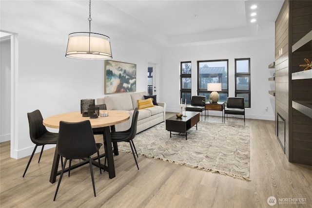 dining area with baseboards, a tray ceiling, recessed lighting, light wood-style flooring, and a fireplace