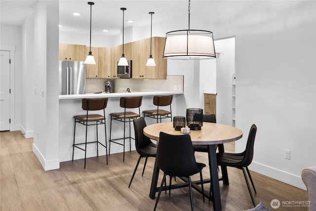 dining room with recessed lighting, baseboards, and light wood-style floors