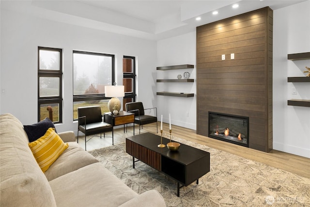 living area with a fireplace, recessed lighting, wood finished floors, and baseboards