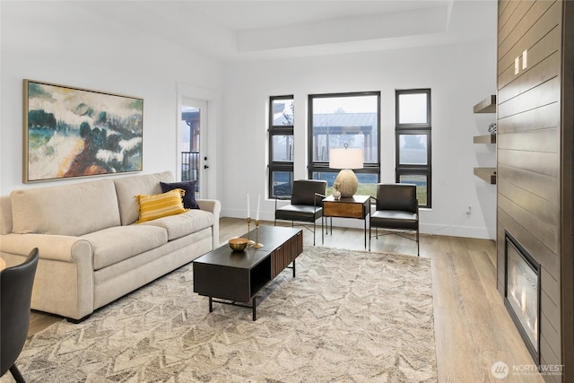 living room featuring a raised ceiling, baseboards, and wood finished floors