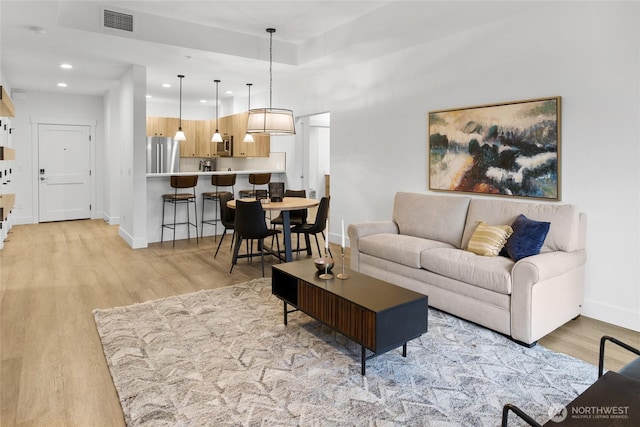 living room featuring visible vents, light wood-style flooring, recessed lighting, and baseboards