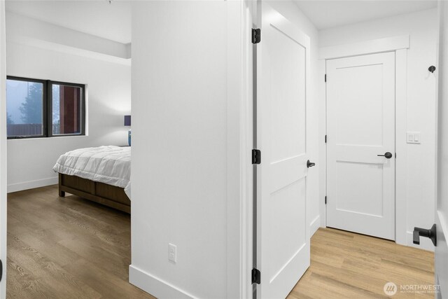 corridor with baseboards and light wood finished floors