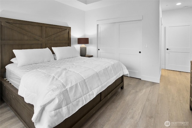 bedroom featuring a closet, recessed lighting, baseboards, and wood finished floors