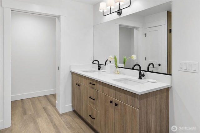 full bath featuring double vanity, wood finished floors, baseboards, and a sink