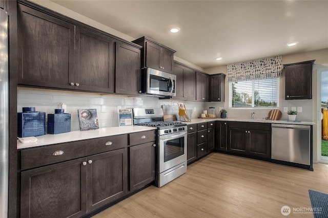 kitchen with light countertops, dark brown cabinets, light wood-style floors, and appliances with stainless steel finishes