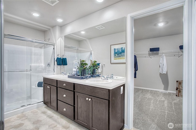 full bath featuring a shower stall, double vanity, and a sink