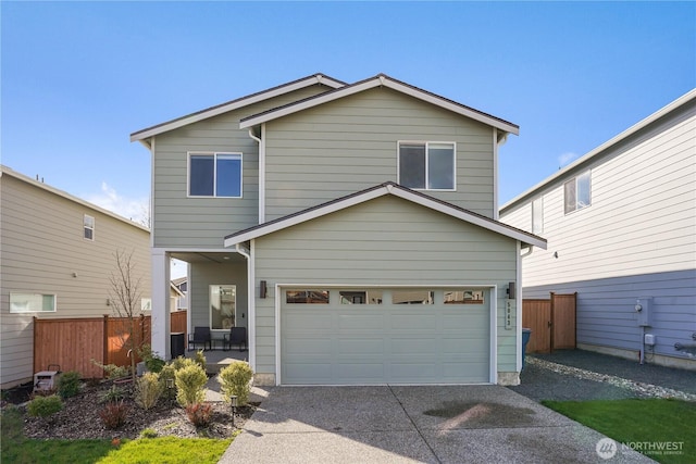 view of front of home with concrete driveway, fence, and a garage