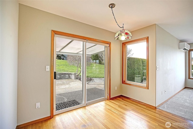 entryway with light wood-type flooring, baseboards, and a wall unit AC
